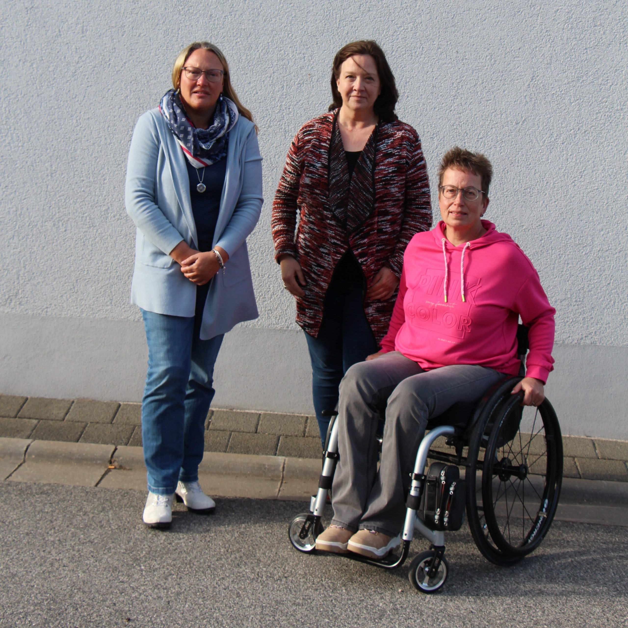 Die neue Vorsitzende und ihre Stellverteterinnen. 2 Frauen stehend und 1 Frau im Rollstuhl.